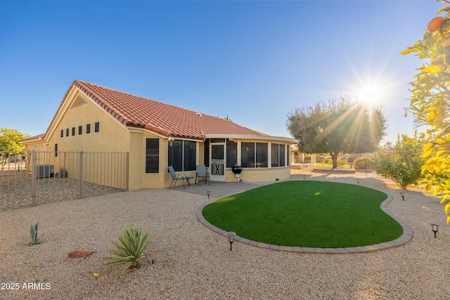 rear view of property with a sunroom, a patio, a lawn, and central AC