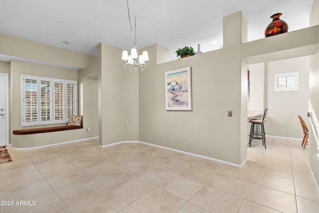 tiled spare room featuring an inviting chandelier