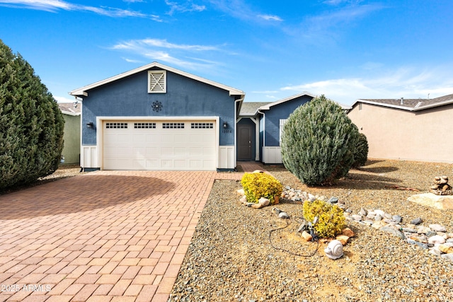 ranch-style house featuring decorative driveway, stucco siding, and an attached garage