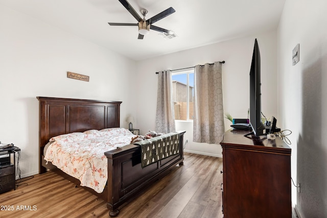 bedroom featuring baseboards, visible vents, a ceiling fan, and wood finished floors