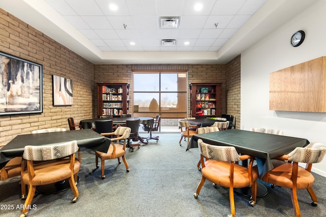 dining space with a paneled ceiling, carpet, brick wall, and visible vents