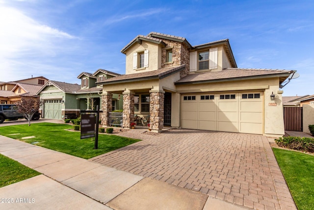 view of front of home featuring stone siding, fence, decorative driveway, a front lawn, and stucco siding