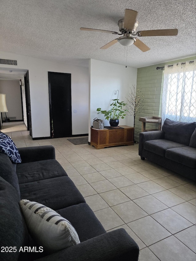 living room featuring light tile patterned floors, a ceiling fan, visible vents, and a textured ceiling