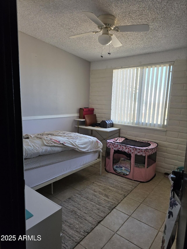 tiled bedroom with ceiling fan and a textured ceiling