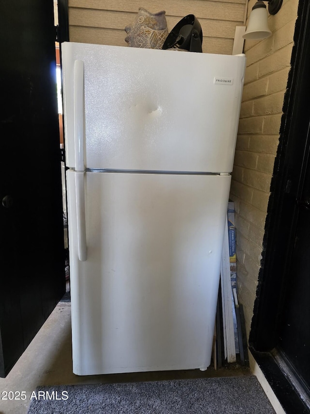 details featuring concrete block wall and freestanding refrigerator