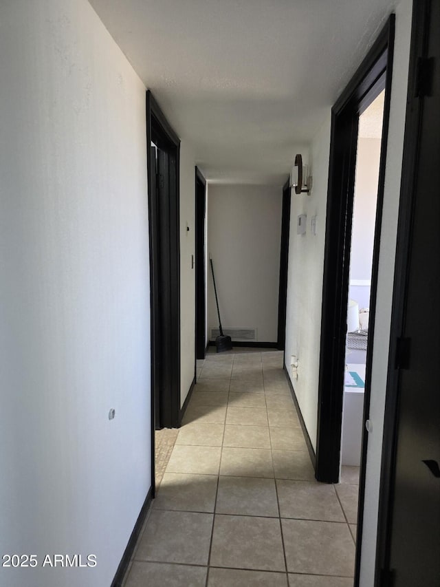 corridor with light tile patterned flooring and baseboards