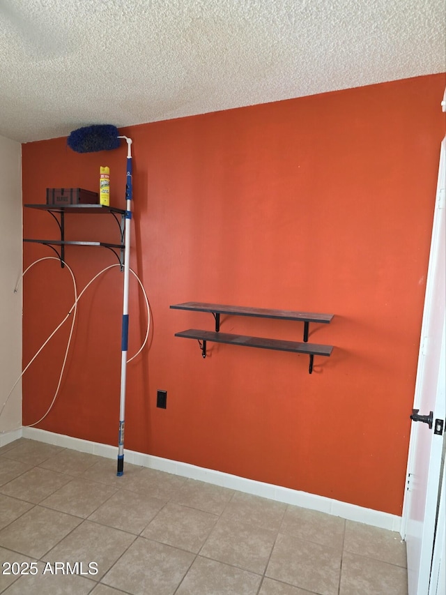 interior space with tile patterned flooring, a textured ceiling, and baseboards