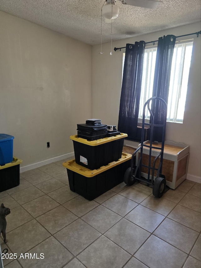 misc room with tile patterned floors, a textured ceiling, and baseboards