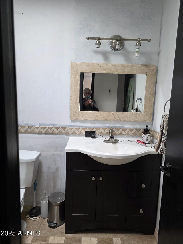 bathroom featuring toilet, vanity, and tile walls