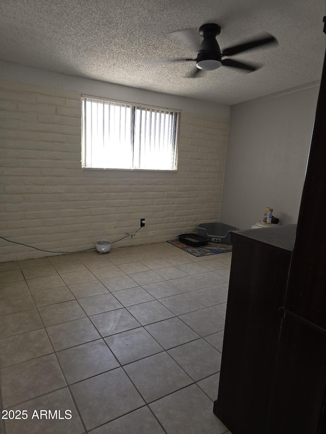 bedroom featuring light tile patterned floors, a textured ceiling, brick wall, and a ceiling fan