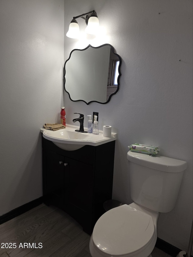 half bathroom with vanity, toilet, and wood finished floors