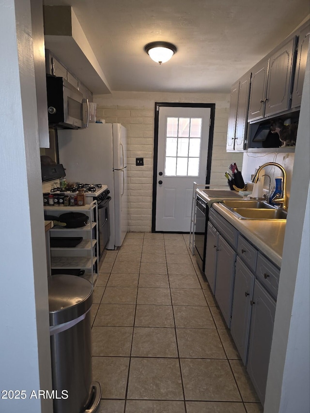 kitchen featuring a sink, stainless steel microwave, black dishwasher, light tile patterned flooring, and gas range