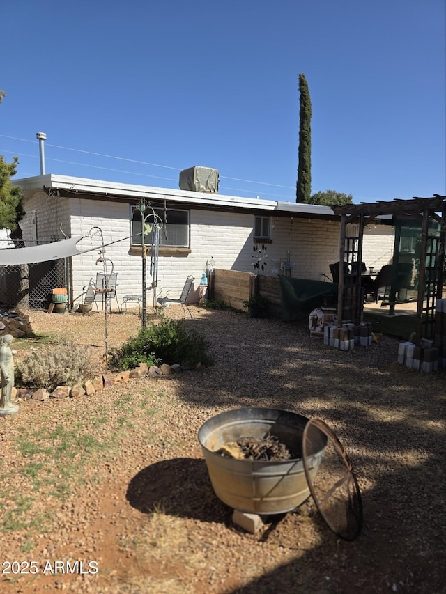 rear view of property featuring brick siding and an outdoor fire pit