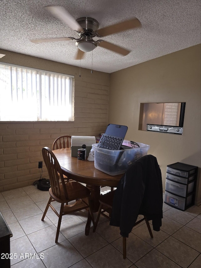 dining area with tile patterned floors, a textured ceiling, brick wall, and a ceiling fan