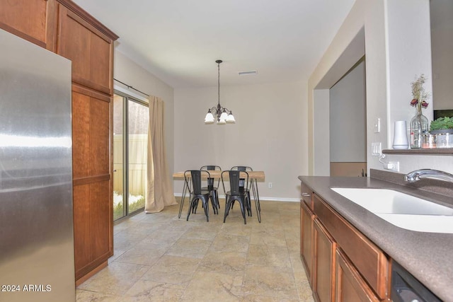 kitchen featuring stainless steel refrigerator, dishwasher, sink, a chandelier, and hanging light fixtures