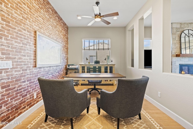 dining area featuring hardwood / wood-style flooring, ceiling fan, and brick wall