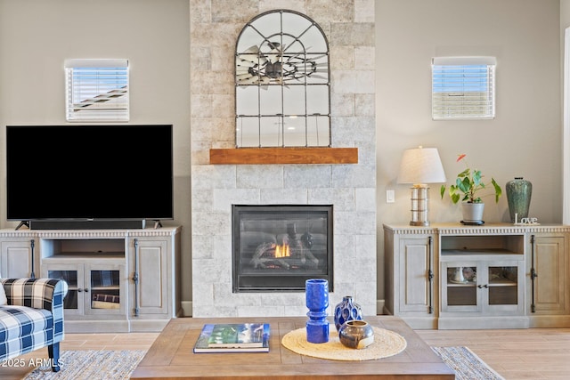 living room with a tile fireplace and light wood-type flooring