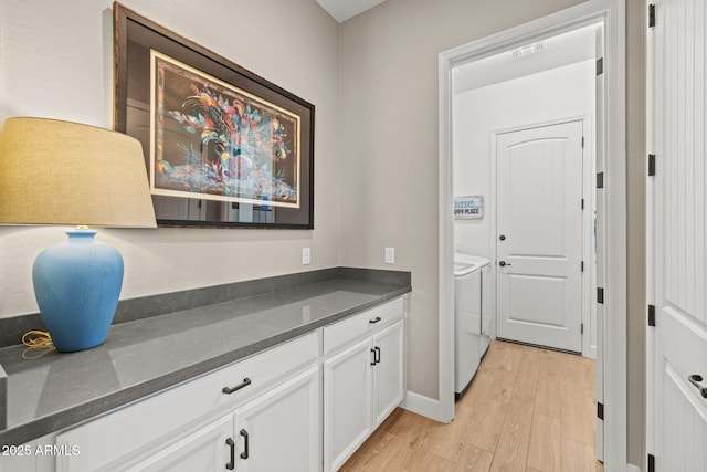 clothes washing area with washer and clothes dryer and light hardwood / wood-style flooring