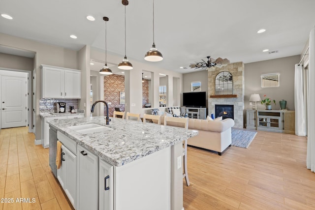 kitchen with pendant lighting, sink, a kitchen breakfast bar, white cabinets, and a center island with sink