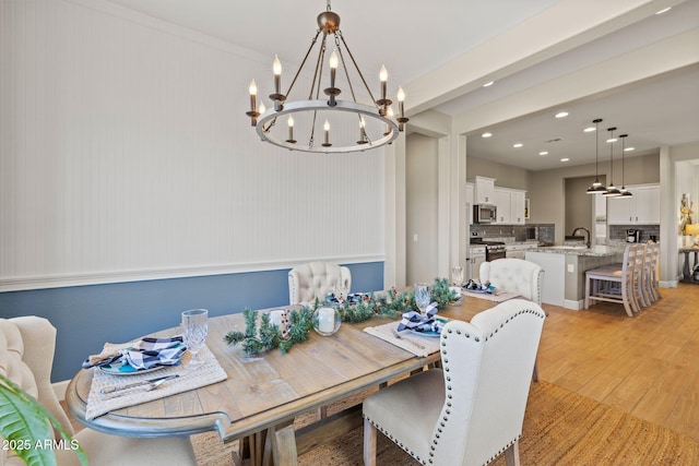 dining room featuring an inviting chandelier, sink, and light wood-type flooring