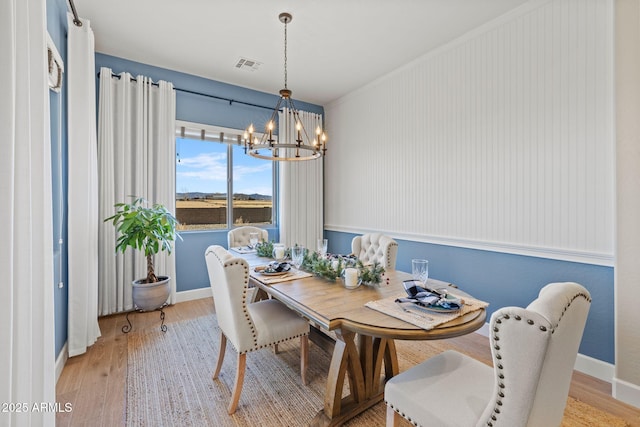 dining space with an inviting chandelier and light hardwood / wood-style flooring