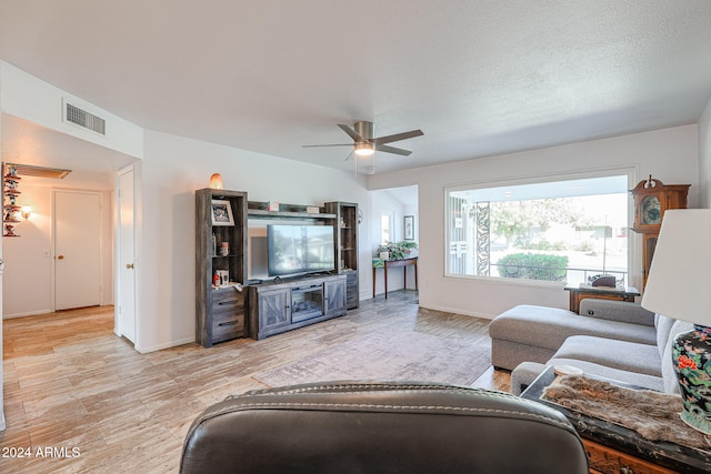 living room with ceiling fan, a textured ceiling, and light wood-type flooring