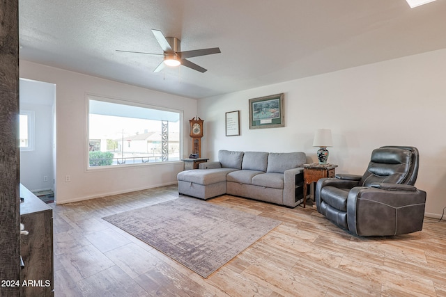 living room with a textured ceiling, light hardwood / wood-style floors, and ceiling fan