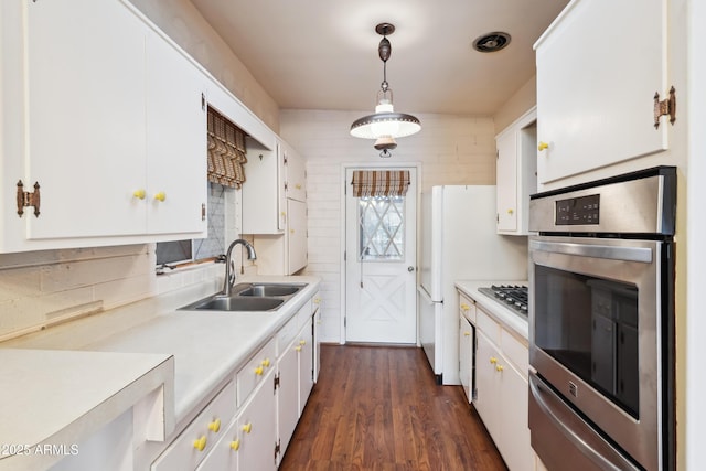 kitchen featuring sink, decorative light fixtures, white cabinetry, dark hardwood / wood-style flooring, and appliances with stainless steel finishes