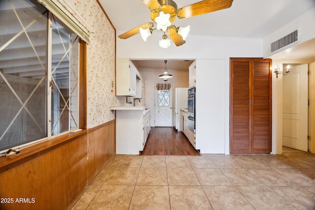 kitchen featuring stainless steel oven, ceiling fan, light tile patterned floors, and white cabinetry