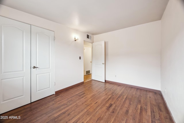 unfurnished bedroom with a closet and dark wood-type flooring