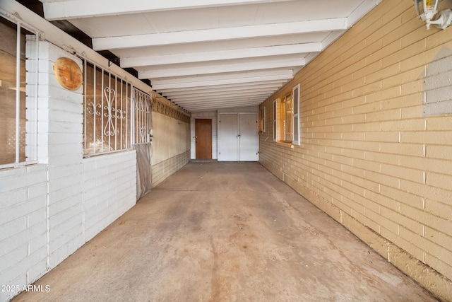 interior space featuring brick wall, concrete floors, and beamed ceiling