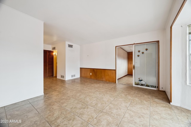 spare room featuring wood walls and light tile patterned floors