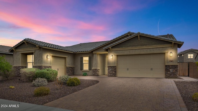 view of front of home featuring a garage, stone siding, and stucco siding