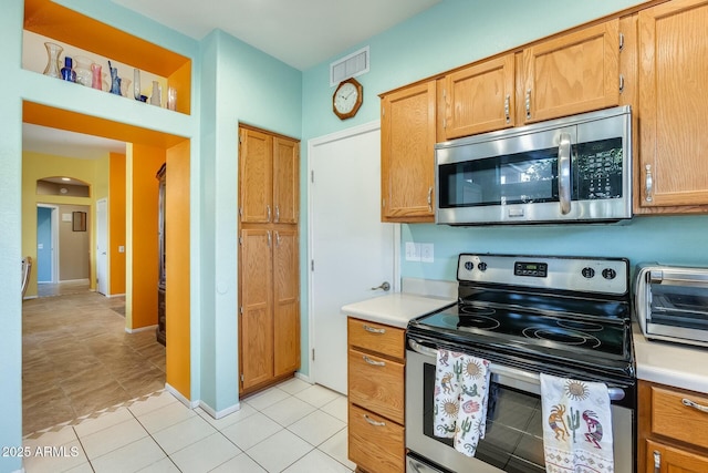 kitchen with visible vents, appliances with stainless steel finishes, light countertops, and arched walkways