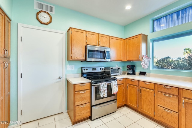 kitchen with light tile patterned flooring, a toaster, stainless steel appliances, visible vents, and light countertops