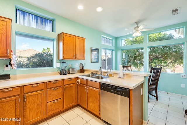 kitchen with a peninsula, a sink, visible vents, dishwasher, and brown cabinetry