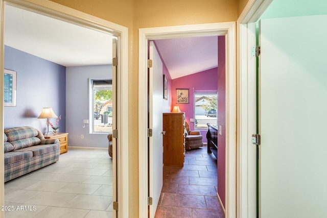 corridor with lofted ceiling and baseboards