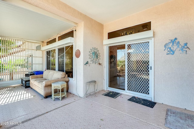 view of exterior entry with a patio area and stucco siding