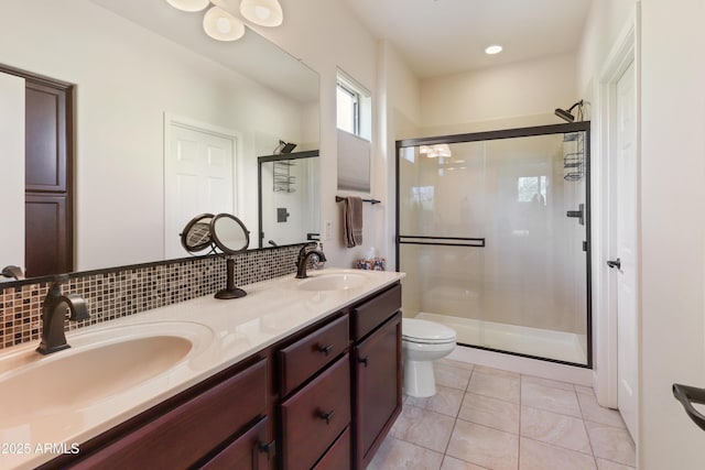 bathroom featuring toilet, tasteful backsplash, a stall shower, and a sink