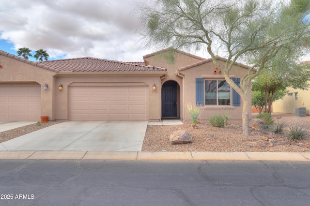 mediterranean / spanish-style home with central air condition unit, an attached garage, driveway, and stucco siding