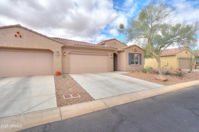 mediterranean / spanish-style house featuring concrete driveway, a tiled roof, an attached garage, and stucco siding