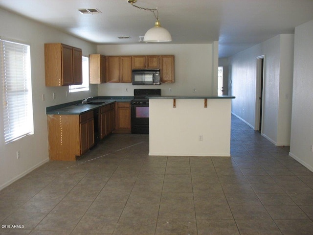 kitchen with pendant lighting, sink, dark tile patterned floors, black appliances, and a breakfast bar