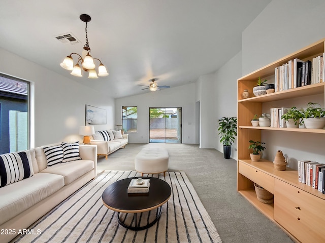 carpeted living room with vaulted ceiling and ceiling fan with notable chandelier