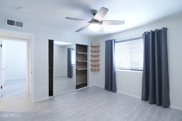 unfurnished bedroom featuring visible vents, a ceiling fan, a closet, light wood finished floors, and baseboards