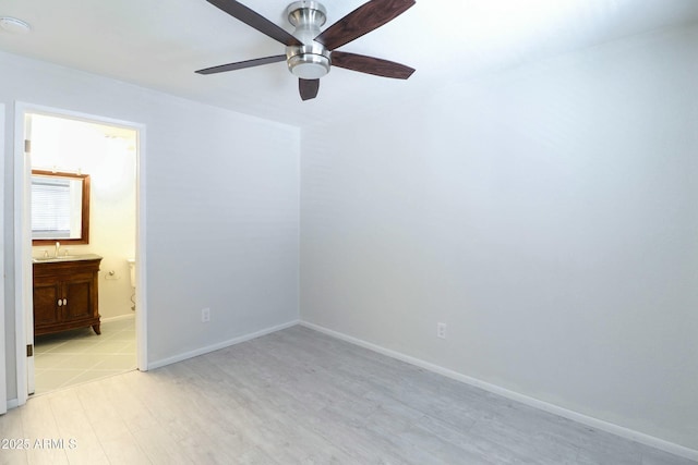 unfurnished bedroom featuring light wood-style flooring, a ceiling fan, a sink, ensuite bath, and baseboards