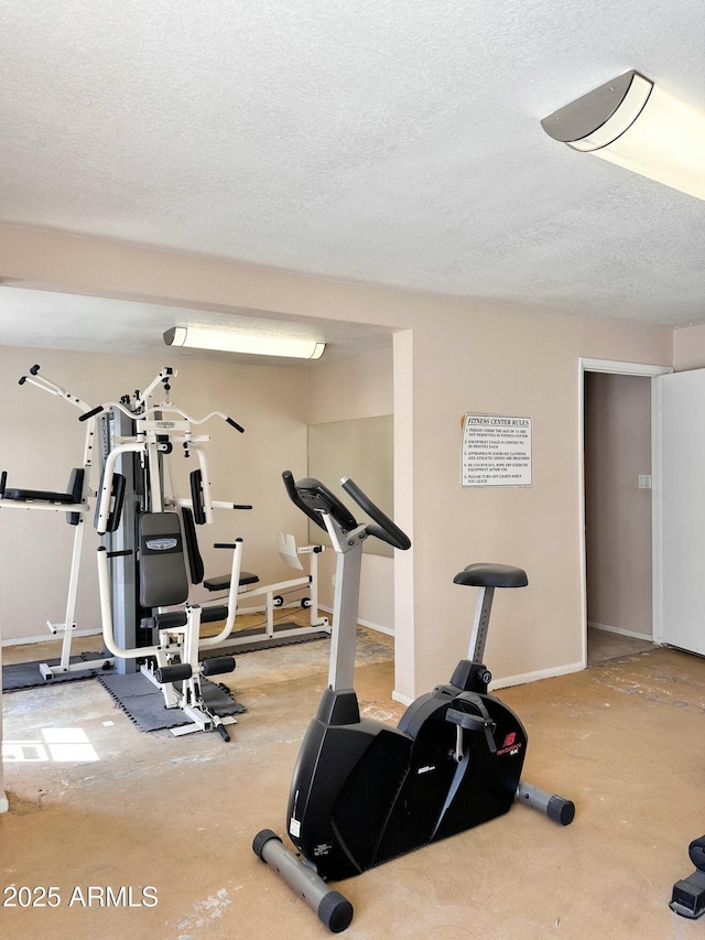 exercise room featuring baseboards and a textured ceiling