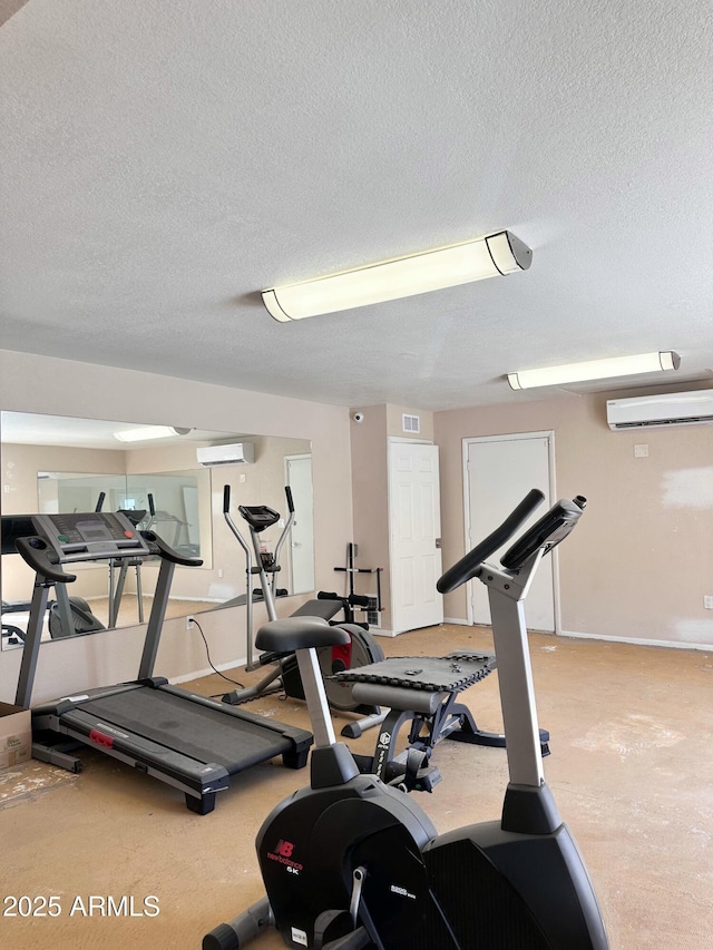 workout room featuring a wall mounted air conditioner, visible vents, and a textured ceiling