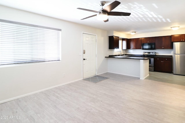 kitchen with dark countertops, light wood finished floors, baseboards, stainless steel appliances, and a ceiling fan