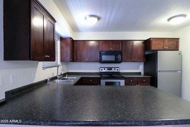 kitchen with a sink, dark countertops, a peninsula, and stainless steel appliances