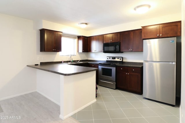 kitchen featuring a sink, dark countertops, stainless steel appliances, a peninsula, and baseboards